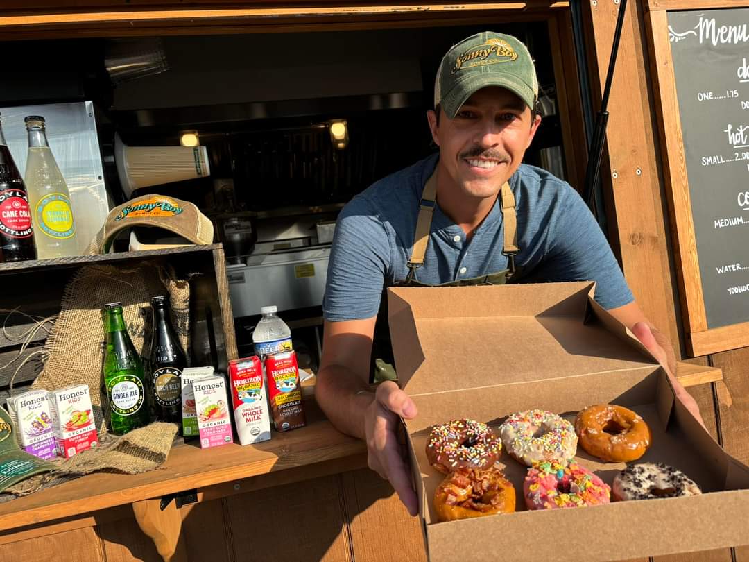 Owner of Sonny Boy Donut Co. handing over a fresh box of donuts